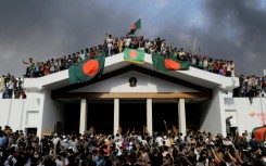 Protesters display Bangladesh's national flag as they storm Sheikh Hasina's palace