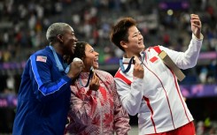 Winners of the women's hammer throw take a selfie with a Samsung flip phone 