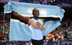 Letsile Tebogo poses with the Botswana flag after a stunning run to win 200m gold at the Paris Olympics 