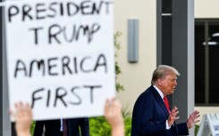 A supporter holds up a sign as former US President and Republican presidential candidate Donald Trump leaves after casting his vote in Florida's primary election on August 14, 2024 in West Palm Beach, Florida