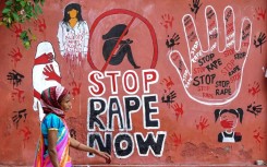 A woman walks past a mural painted on a wall in Ajmer condemning the rape and murder of a doctor in India's West Bengal state