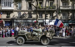 Reenactors dressed in wartime uniforms parade on wartime military vehicles during a reenactment marking the 80th anniversary of the liberation of Paris from the Germans during World War II