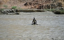 A Sudanese man wades through muddy waters after the collapse of the Arbaat Dam, 40km north of Port Sudan following heavy rains and torrential floods