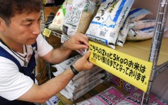 A supermarket worker puts up a sign telling customers they are restricted to one bag of rice each in Tokyo