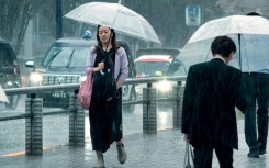 People carrying umbrellas walk across a street in Tokyo on August 30. Typhoon Shanshan weakened to a tropical storm but was still dumping heavy rains as it slowly churned through Japan