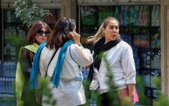 Women chat on a street in Tehran on the second anniversary of the protest movement