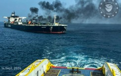 This handout picture provided by EUNAVFOR ASPIDES shows a vessel with a rope extended toward the Greek-owned oil tanker Sounion as smoke and fire billows from it, off the coast of Hodeida in the Red Sea