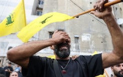 A Lebanese man clutching a Hezbollah flag is seen at funeral for people killed in pager attacks