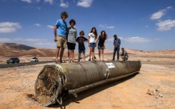 People stand on top of the remains of an Iranian missile in the Negev desert near Arad in southern Israel