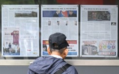 A man walks past a newspaper displayed on a street in Seoul with coverage on North Korea's decision to deploy thousands of soldiers to Russia