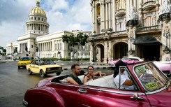 Tourists ride in a classic American car through the streets of Havana 