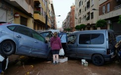 Residents stand in front of piled up cars following deadly floods in Alfafar neighbourhood, south of Valencia