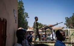 A Sudanese army soldier mans a machine gun on top of a military pickup truck outside a hospital in Omdurman