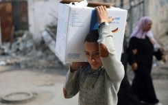 A boy carried a box of humanitarian aid back to his home in central Gaza's Al-Bureij refugee camp