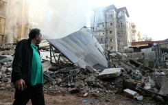 A man walks past the rubble of a building levelled by an Israeli air strike in Beirut's southern suburbs on Saturday