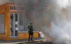 A Mozambique soldier tries to put out a burning tyre during a protest in Maputo Wednesday