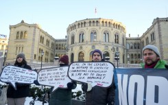 Protesters hold placards during a demonstration against seabed mining outside the Norwegian Parliament building in Oslo