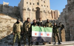 Anti-government fighters hold an opposition flag as they pose for a picture at the entrance of Aleppo's landmark citadel