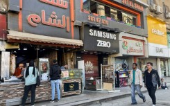 People pass a Syrian restaurant in western Cairo, where Syrian businesses have clustered, and the air buzzed with celebration after the fall of Bashar al-Assad in Damascus