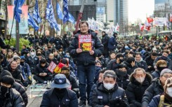 Kim Sung-tae (C), a 52-year-old worker at a company that makes car parts, poses with a placard reading "Insurrectionist Yoon Suk Yeol. Impeach! Arrest!"