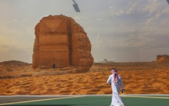 A COP16 delegate walks past a giant poster of a Saudi archaeological site at the start of the UNCCD talks