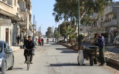 A Syrian man rides his bicycle down a street in the town of in Qusayr in Syria's central Homs province