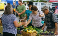 People shop for fresh produce and food at a farmer's market on June 29, 2021, in Homewood, Alabama