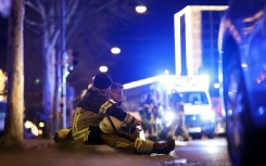 Two rescuers sit on the ground to rest after a car crashed into a crowd at a Christmas market injuring more than 60 people in Magdeburg, eastern Germany  
