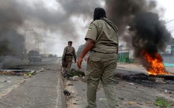 Mozambican security forces next to a burning barricade in Maputo on Tuesday