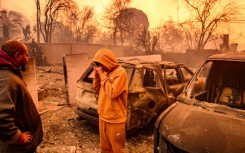 Lebron Jones wipes his eyes while viewing his burned home