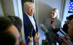 US President Donald Trump speaks with the press, alongside White House Press Secretary Karoline Leavitt (R), on board Air Force One 